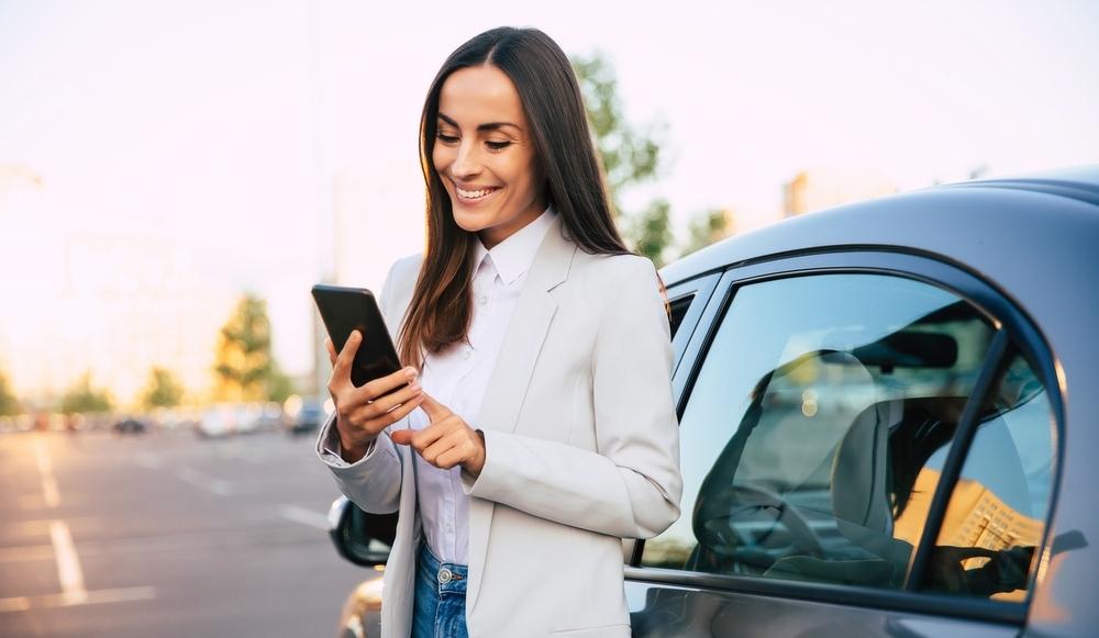 Driver with vehicle reviewing Ontario insurance guide on smartphone